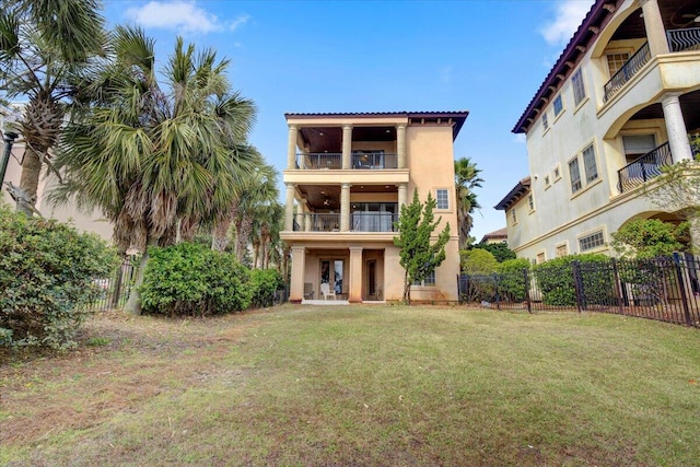 rear view of house featuring a balcony and a lawn