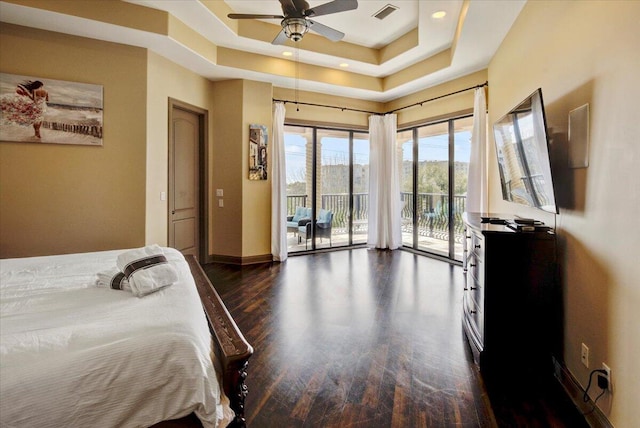 bedroom featuring access to outside, dark hardwood / wood-style floors, a raised ceiling, and ceiling fan