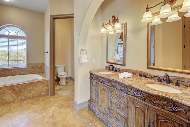 bathroom featuring tiled tub, vanity, and toilet