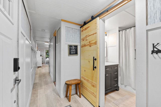 corridor with a barn door and light hardwood / wood-style flooring