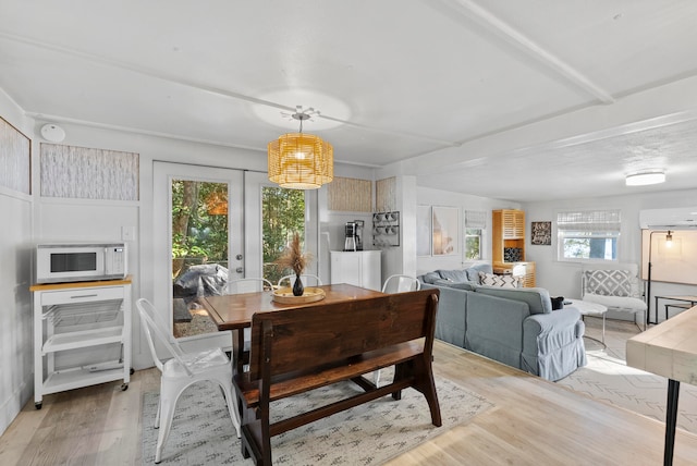 dining room featuring plenty of natural light, light hardwood / wood-style flooring, a wall mounted AC, and french doors