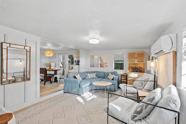 living room with a textured ceiling, a wealth of natural light, light hardwood / wood-style floors, and a wall mounted air conditioner