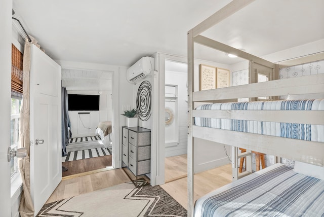 bedroom with a wall unit AC and light hardwood / wood-style flooring