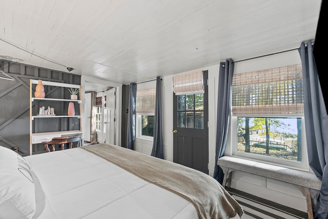 bedroom with multiple windows and wooden walls