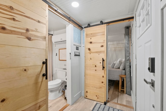 bathroom featuring toilet, a wall mounted air conditioner, and hardwood / wood-style flooring