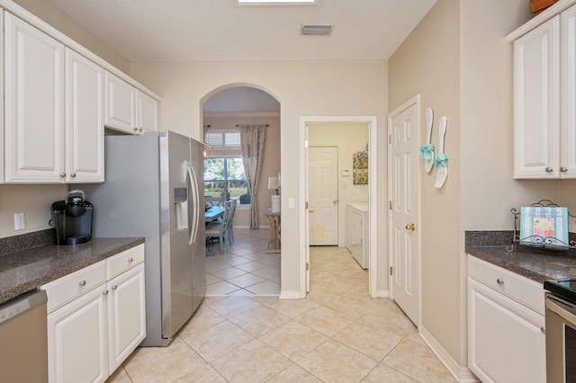 kitchen with light tile patterned floors, a textured ceiling, stainless steel appliances, and white cabinetry