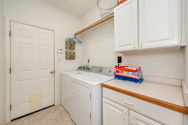 laundry room with cabinets, light tile patterned floors, and washing machine and clothes dryer