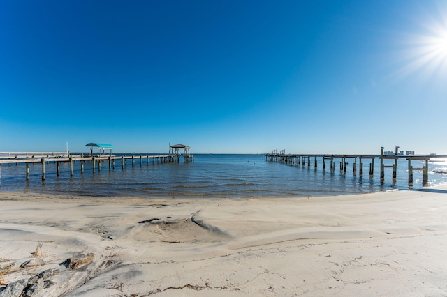 view of dock featuring a beach view and a water view