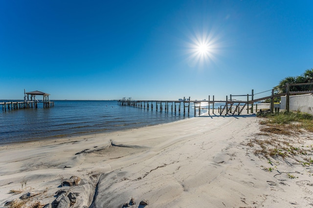 view of dock featuring a beach view and a water view