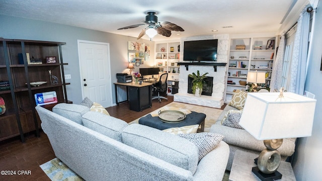 living room with ceiling fan, a stone fireplace, and dark hardwood / wood-style flooring