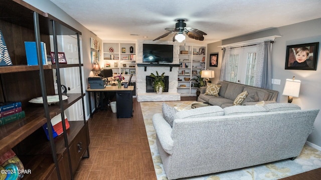 living room with a textured ceiling, built in features, and ceiling fan