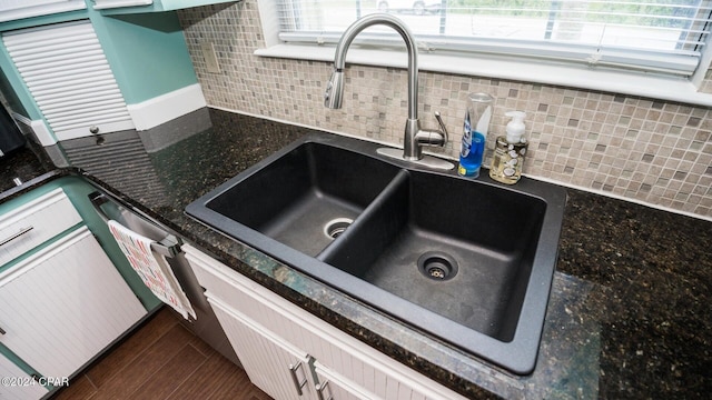 interior details featuring backsplash, sink, white cabinets, and stainless steel dishwasher