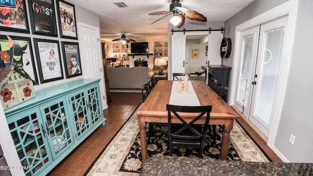 dining area with a barn door, ceiling fan, hardwood / wood-style floors, and a textured ceiling