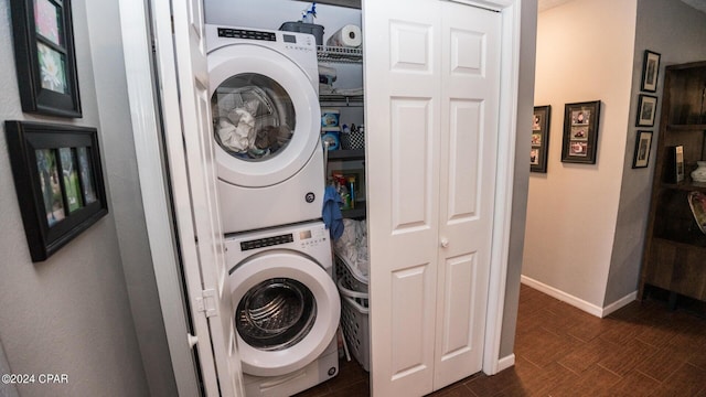 washroom featuring stacked washer and dryer and dark wood-type flooring