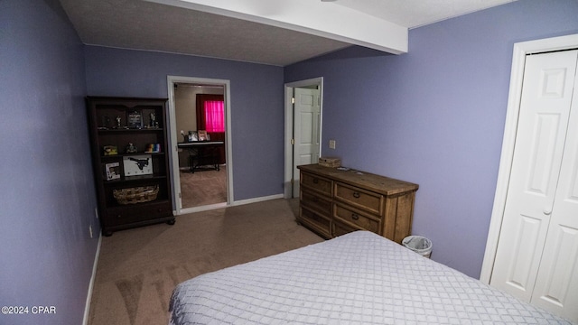 bedroom featuring dark colored carpet, a closet, and beamed ceiling