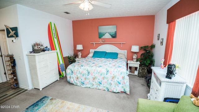 bedroom featuring ceiling fan, carpet floors, a textured ceiling, and multiple windows