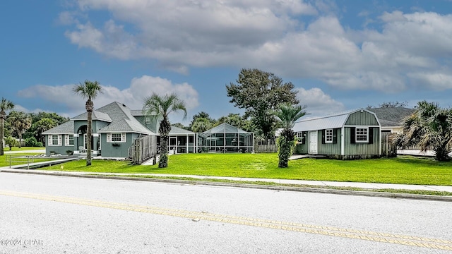 view of front of property featuring glass enclosure, an outdoor structure, and a front lawn