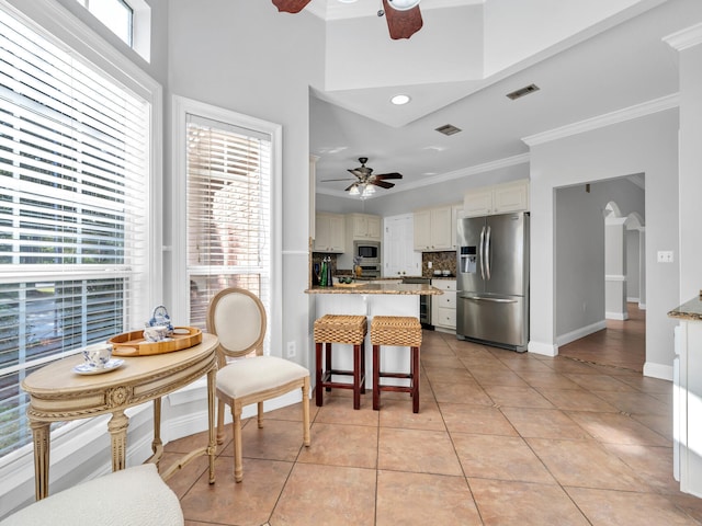 dining room with crown molding, light tile patterned floors, visible vents, ceiling fan, and baseboards