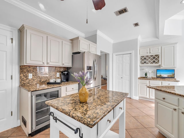 kitchen featuring light tile patterned floors, wine cooler, stone counters, backsplash, and stainless steel fridge