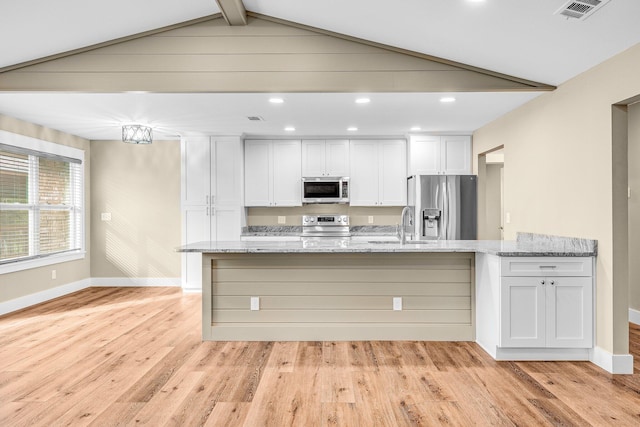 kitchen with light hardwood / wood-style floors, light stone countertops, white cabinetry, and appliances with stainless steel finishes