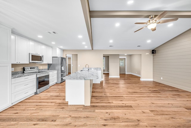 kitchen with light stone counters, an island with sink, light hardwood / wood-style floors, white cabinets, and appliances with stainless steel finishes