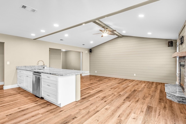 kitchen with light stone counters, white cabinets, light hardwood / wood-style floors, and wood walls