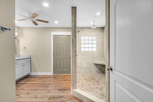 bathroom with a tile shower, ceiling fan, hardwood / wood-style floors, and vanity