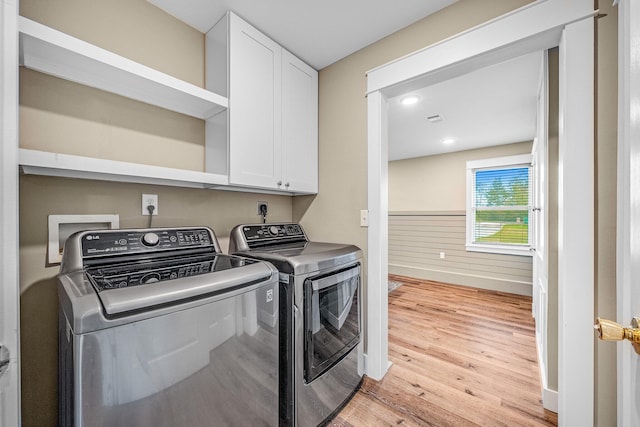 clothes washing area featuring cabinets, separate washer and dryer, and light hardwood / wood-style flooring