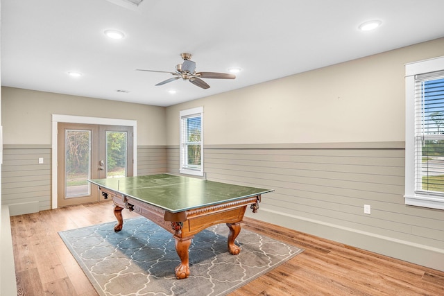 rec room with ceiling fan, light hardwood / wood-style flooring, and wood walls