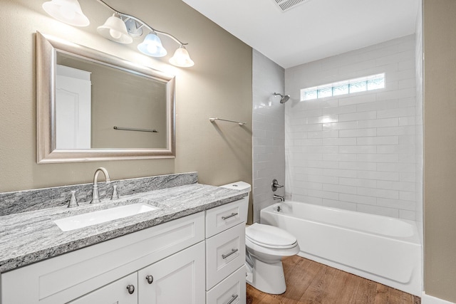 full bathroom featuring vanity, toilet, wood-type flooring, and tiled shower / bath