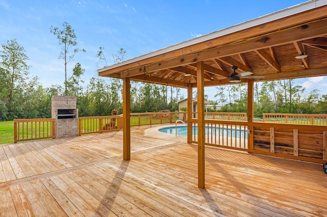 deck featuring a fenced in pool, ceiling fan, and exterior fireplace