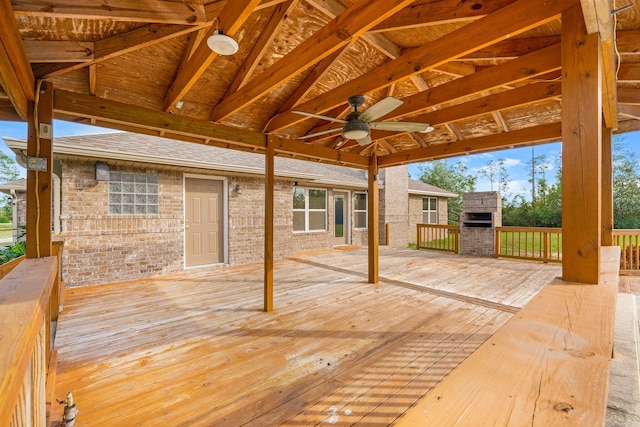 wooden deck with an outdoor stone fireplace and ceiling fan