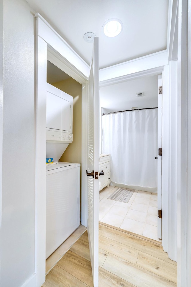 bathroom with wood-type flooring and stacked washer / drying machine