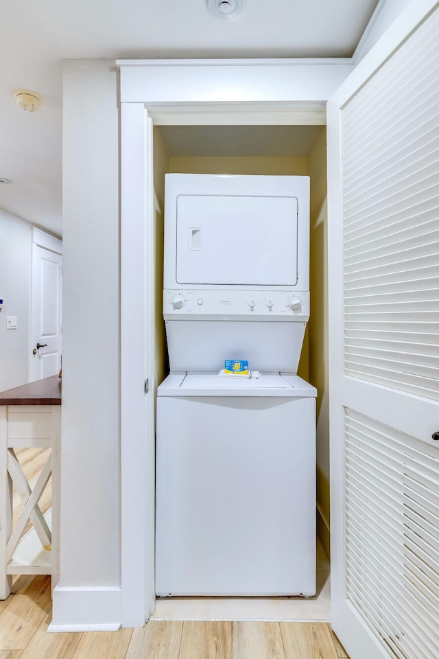 laundry room featuring light wood-type flooring and stacked washing maching and dryer