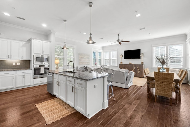 kitchen featuring a kitchen island with sink, white cabinets, sink, dark stone countertops, and appliances with stainless steel finishes