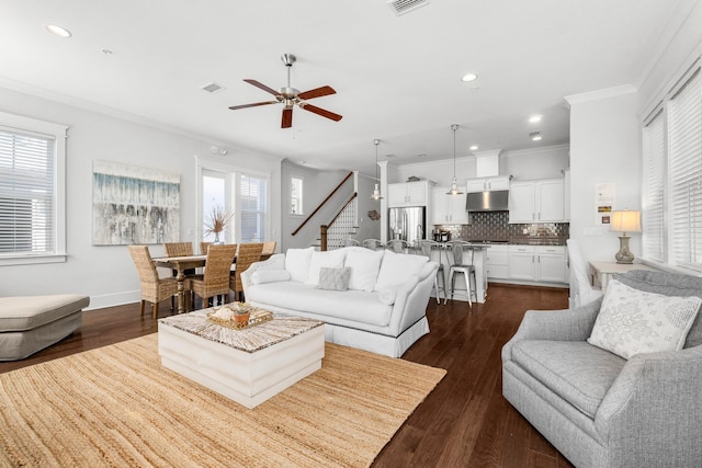 living room with ceiling fan, a healthy amount of sunlight, ornamental molding, and dark wood-type flooring