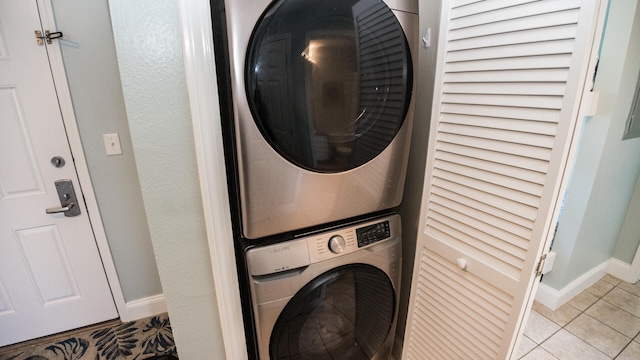 clothes washing area with light tile patterned floors and stacked washing maching and dryer