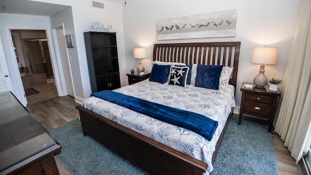 bedroom with ensuite bathroom, wood-type flooring, and a closet