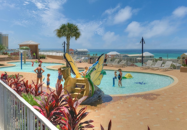 view of pool with a water view and a patio