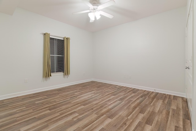 spare room featuring a ceiling fan, baseboards, and light wood finished floors