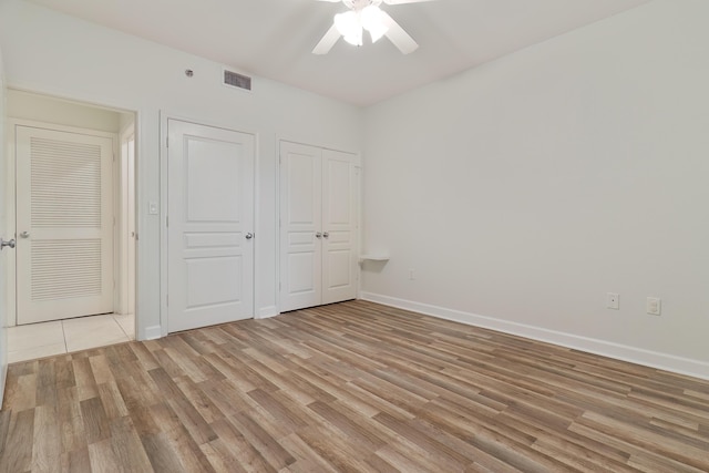 unfurnished bedroom with baseboards, visible vents, ceiling fan, and light wood-type flooring