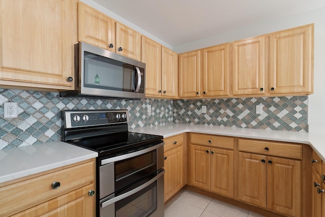 kitchen featuring backsplash, light countertops, appliances with stainless steel finishes, and light tile patterned floors