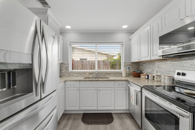 kitchen featuring backsplash, sink, light wood-type flooring, appliances with stainless steel finishes, and white cabinetry