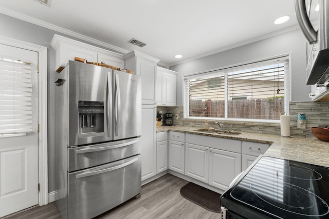 kitchen with backsplash, white cabinets, sink, stainless steel fridge, and light hardwood / wood-style floors