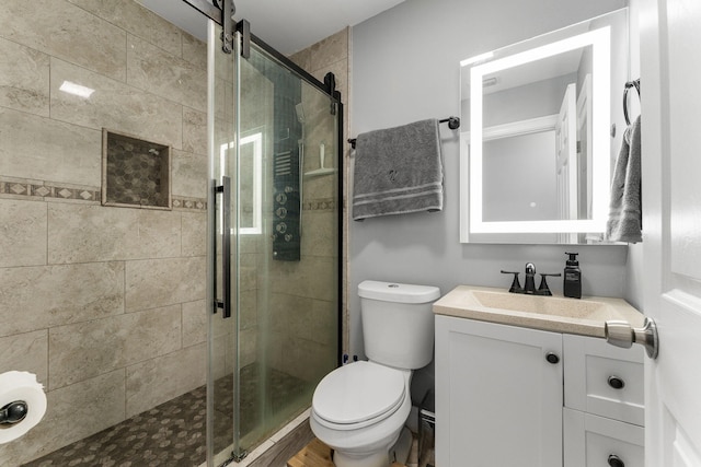 bathroom featuring hardwood / wood-style floors, vanity, toilet, and a shower with door