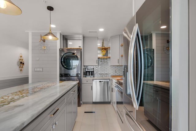 kitchen featuring light stone counters, appliances with stainless steel finishes, stacked washing maching and dryer, open shelves, and backsplash