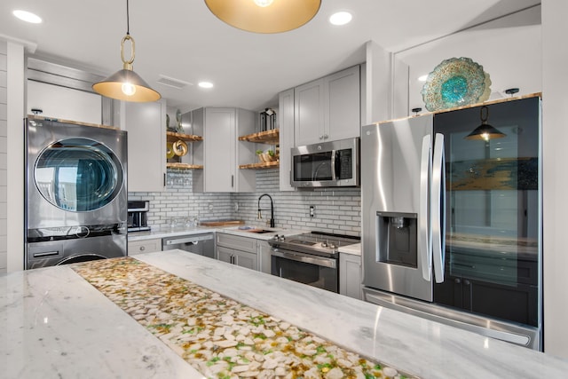 kitchen featuring stacked washer and dryer, a sink, stainless steel appliances, open shelves, and backsplash