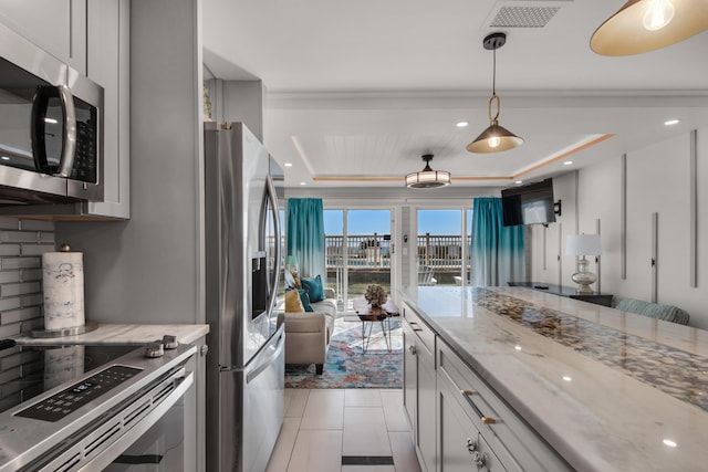 kitchen featuring light stone counters, a tray ceiling, tasteful backsplash, visible vents, and appliances with stainless steel finishes