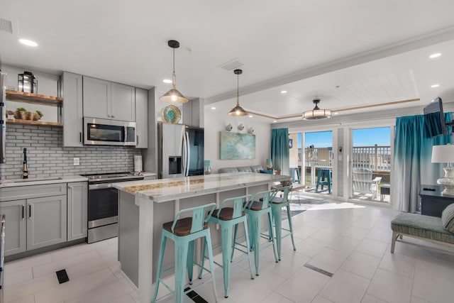 kitchen with a sink, appliances with stainless steel finishes, gray cabinets, and tasteful backsplash