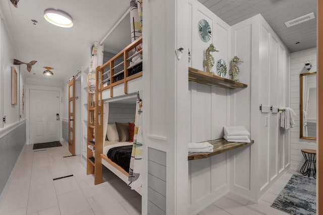 mudroom with visible vents, a decorative wall, and light tile patterned flooring